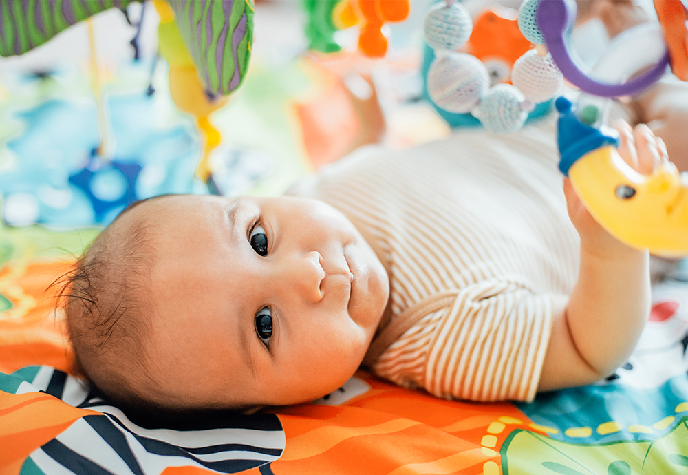 infant laying on a playmat