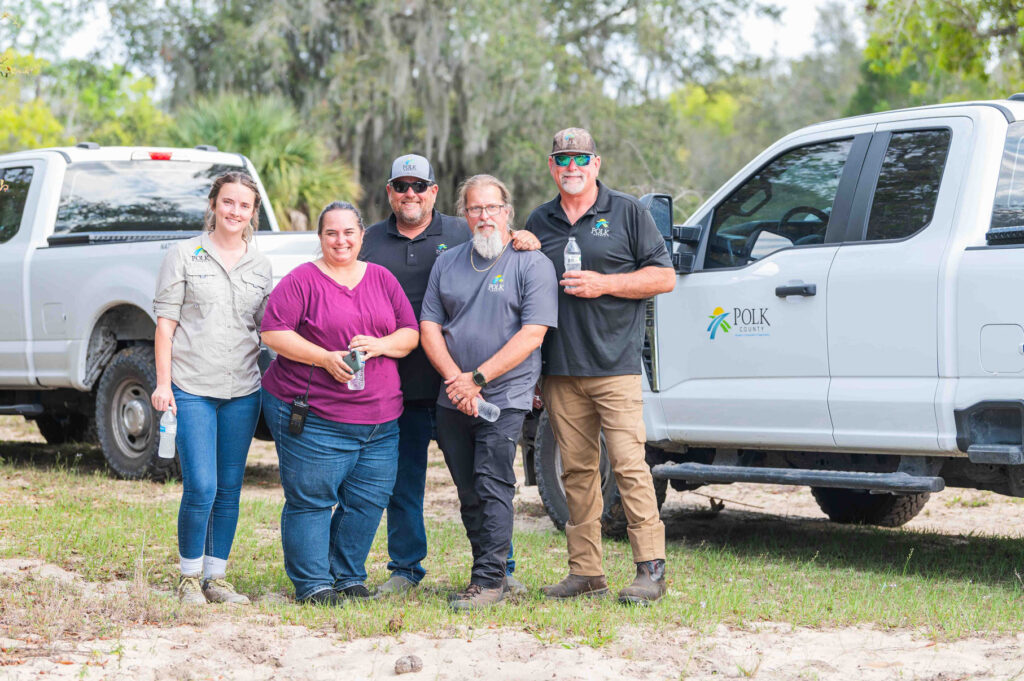 Polk County Technical Assessment Group (TAG) posing for photo on trail with trucks