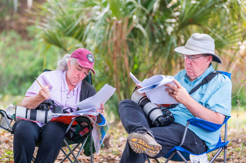Miembros del Grupo de Evaluación Técnica del Condado de Polk leyendo documentos en sillas de camping
